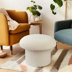 a living room with two chairs and a footstool in front of a potted plant