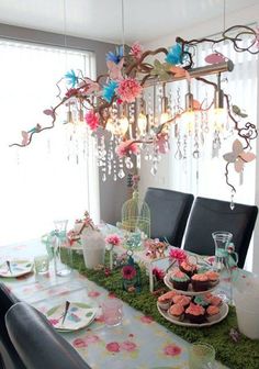 a dining room table with plates and cups on it next to a chandelier