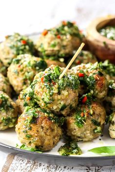 a white plate topped with meatballs covered in pesto