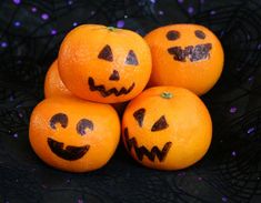 four oranges with faces painted on them sitting in a pile next to each other