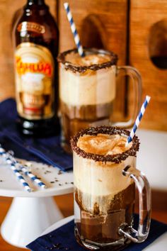 two mugs filled with ice cream and chocolate on top of a blue napkin next to a bottle of beer