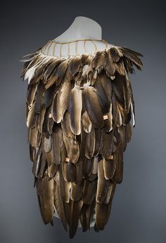 a mannequin's head with feathers hanging from the top and bottom of it