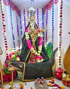 an idol is sitting in the middle of a stage with flowers and garlands around it