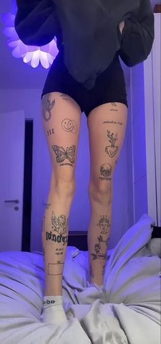 a person with tattoos on their legs standing on a bed