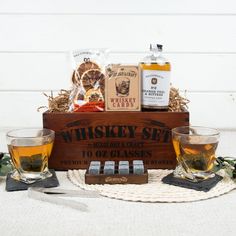 two glasses of whiskey sit next to each other in front of a wooden box filled with liquor