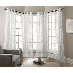 a living room with white curtains and a chair