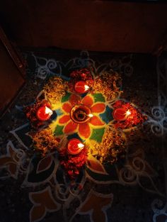 a lit diya is on the ground with candles