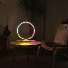 a round light sitting on top of a table next to a chair and potted plant