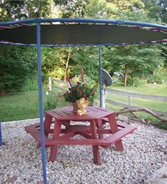 a picnic table with a potted plant on it in the middle of a gravel area