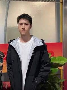 a young man standing in front of a plant