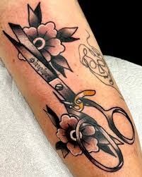 a tattoo with scissors and flowers on it