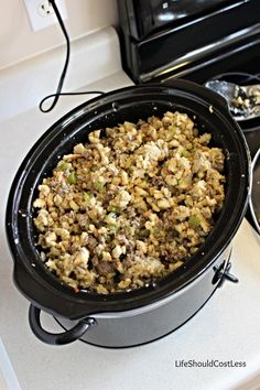 a crock pot filled with stuffing sitting on top of a stove next to an oven