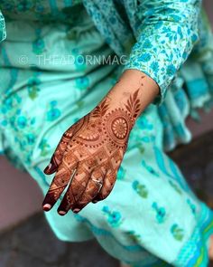 a woman's hand with hennap on it and blue floral print dress