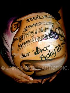 a woman's belly with music notes painted on the side and hands holding it