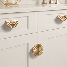 a white cabinet with gold handles and knobs on the front, along with other cabinets