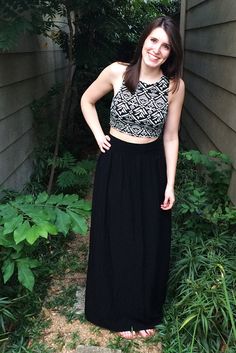 a woman standing in front of a house wearing a black and white cropped top