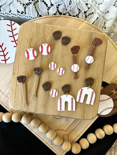 a wooden tray topped with lots of different shaped earrings on top of a table next to balls