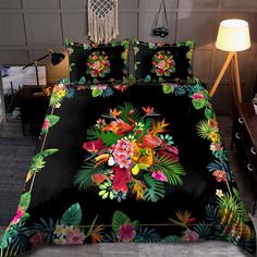 a bed covered in a black comforter with colorful flowers and leaves on the cover