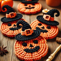 crocheted pumpkin coasters with black and orange hats on them sitting on a wooden table