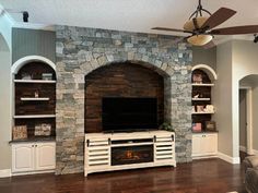 a living room with stone fireplace and built - in entertainment center