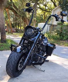 a black motorcycle parked on the side of a road next to a tree filled street