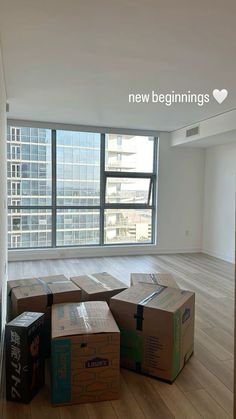 several boxes are stacked on the floor in an empty room with large windows and wooden floors