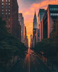 an empty city street at sunset with tall buildings in the back ground and cars on the road