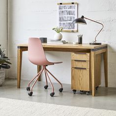 a desk with a pink chair next to it and a potted plant on the side