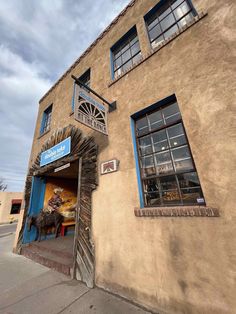 an old building with blue windows on the front and side doors that are open to let people know where they are going