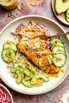 a white plate topped with salmon, cucumber and radishes on top of a table