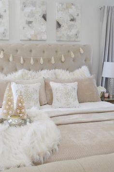 a bed with white fur and pillows in a bedroom next to two pictures on the wall