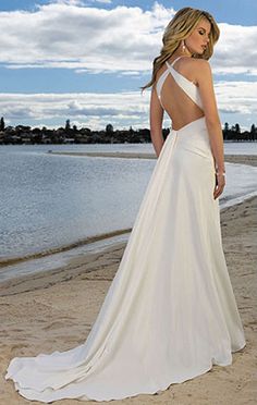 a woman is standing on the beach wearing a white dress and looking back at the camera