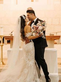 a bride and groom kissing in front of the alter