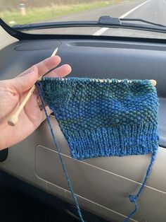 someone is knitting something on the dashboard of their car