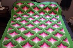 a green and pink blanket on top of a bed