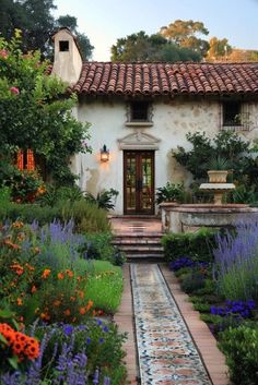 a house with lots of flowers and plants around the front door, along with steps leading up to it