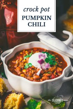 crock pot pumpkin chili with sour cream and cilantro on top in a white bowl