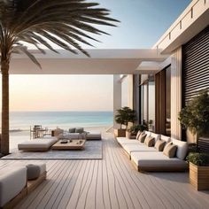 an outdoor living area with couches, tables and palm trees in front of the ocean