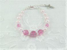 "Tiny pale pink pearls, rose Swarovski crystals and a dark pink rose lampwork bead are strung into a darling infant girl bracelet. A silver plated extension chain makes this tiny bracelet adjustable from 4 1/2\" to 5 3/4\" in length. The central bead is a dark pink Czech glass lampwork rose bead. The 4mm pale pink pearls are complimented with 4mm round rose Swarovski crystals. The 6mm Rose designed lampwork bead, along with the 6mm rose crystals are spaced with tiny silver spacer beads. A silver Personalized Pink Pearl Bracelet For Birthday, Adjustable Pink Jewelry For Baptism, Adjustable Pink Pearl Bracelet For Weddings, Elegant Pink Bracelets For First Communion, Personalized Pink Charm Bracelet For Wedding, Personalized Pink Pearl Bracelet With Round Beads, Elegant Pink Rosary Bracelet For Wedding, Elegant Pink Wedding Rosary Bracelet, Pink Beaded Bracelets With 8mm Beads For Birthday