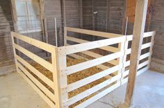 the inside of a barn with hay in it's stall and wooden posts on the floor