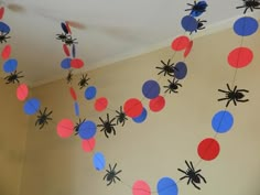 spider decorations hanging from the ceiling with red, white and blue paper balls on them