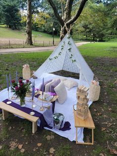 a table set up for a party with candles and flowers on it in the grass