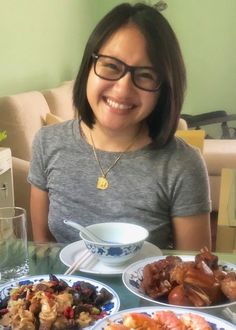 a woman sitting at a table with plates of food in front of her, smiling for the camera