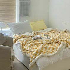 an unmade bed with yellow and white blankets