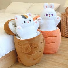 two stuffed animals are sitting in the shape of pumpkins on a wooden floor next to a bed