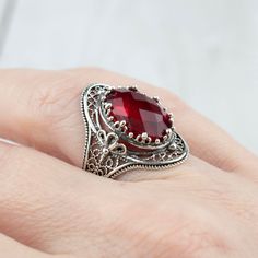 "Unveil the elegance with our Handcrafted Sterling Silver Flower-Detailed Cocktail Ring. Masterfully designed with intricate filigree art, this 925 sterling silver ring captures the essence of nature's beauty through its detailed flower motif. It's adorned with a stunning 10x14 mm double-side faceted oval cut gemstone, available in the fiery lab-created Ruby or the enchanting lab-created Emerald. Celebrate the essence of birthstones with our offerings: the Ruby, a symbol of passion and love for those born in July, or the Emerald, representing renewal and hope for May birthdays. Specially crafted in 16 different sizes, from a delicate size 5 to a bolder 12.5, including half sizes, ensuring a tailored fit for every hand. Looking for the ideal gift? Our statement cocktail ring encapsulates th Exquisite Oval Filigree Ring, Exquisite Oval Filigree Promise Ring, Oval Silver Ruby Filigree Ring, Ornate Filigree Ring For Promise, Oval Silver Ruby Ring With Filigree, Ornate Filigree Promise Ring, Exquisite Silver Oval Filigree Ring, Ornate Oval Filigree Ring With Stone Setting, Ornate Oval Filigree Ring As Gift