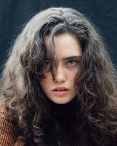 a woman with long grey hair is looking at the camera