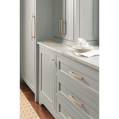 a kitchen with gray cabinets and white counter tops, gold handles on the door knobs