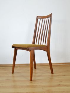 a wooden chair sitting on top of a hard wood floor next to a white wall