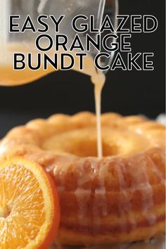 an orange bundt cake being drizzled with icing and sliced oranges